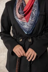 Chaquetón color beige de corte recto y largo, con cierre frontal mediante botones y lazo ajustable en la cintura. Presenta cuello en V, bolsillos laterales con solapa y mangas largas.