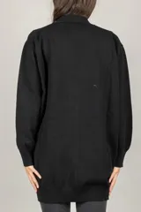 Cardigan oversize negro con escote en V, cierre frontal de botones y broches decorativos con perlas en el lado izquierdo.