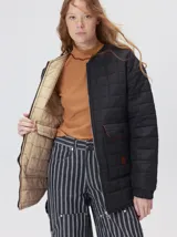 Campera reversible capitoneada con cierre frontal. Un lado es de color negro y el otro es de color beige, ambos con diseño acolchado. Cuenta con cuello redondo, mangas largas y bolsillos laterales.