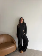 Conjunto de dos piezas color gris melange, confeccionado en tela de lanilla, compuesto por un buzo de manga larga con diseño cruzado al frente y un pantalón largo de corte holgado y tiro alto.