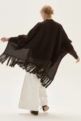 Ruana tejida en lana de cordero con diseño de sectores calados y terminación con flecos en los bordes.