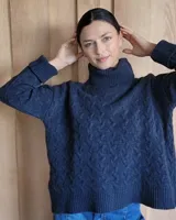 Sweater de lana color crudo con cuello alto y diseño trenzado.