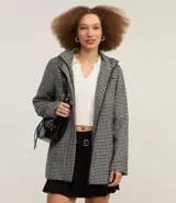 Saco largo con capucha y estampado pied de poule en blanco y negro. Tiene cuello alto, cierre con botones y cremallera, bolsillos y mangas largas.