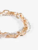 Pulsera de triple cadena, una dorada de eslabones grandes, una plateada con strass y una plateada de bolitas.