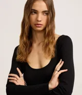 Vestido midi negro con parte superior de rib acanalado, escote en U y mangas largas. La falda es de tricolina lisa.