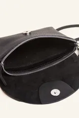Cartera tipo sobre de cuero color marrón, con solapa frontal redondeada que presenta un detalle circular grabado. Incluye correa larga ajustable y extraíble, cierre principal y broche de seguridad.
