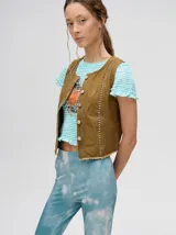 Chaleco de denim liviano con cierre frontal de botones metálicos, detalle de apliques metálicos verticales y ruedo con terminación desflecada.