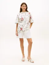 Remera de manga corta Tommy Hilfiger de corte relajado, color blanco con estampado floral de contornos azul oscuro y detalles en rojo. Presenta cuello redondo y diseño holgado.