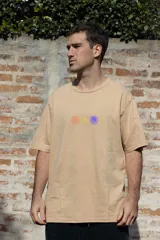 Remera color beige de manga corta con cuello redondo y estampado de tres flores en el frente: naranja, amarilla y violeta. Confeccionada en algodón premium.