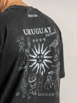 Remera oversize de algodón color negro con efecto lavado, que presenta un estampado gráfico en la espalda con motivos icónicos de la cultura uruguaya en color blanco.