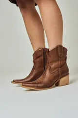Botas texanas de cuero color chocolate, con diseño de costuras decorativas en la puntera y el lateral. Presentan un taco cuadrado de madera y cierre lateral interno.