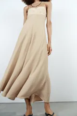 Vestido midi de color beige con escote recto adornado con un panel de encaje semitransparente, tirantes finos ajustables y falda fluida con cierre lateral con cremallera oculta.