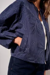 Campera bomber de algodón color azul, con diseño de bordado floral en tono sobre tono, cierre frontal y mangas largas con puños elásticos.