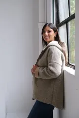 Tapado de paño con capucha, color beige, con cierre frontal, bolsillos laterales y puños vueltos en tono más claro.