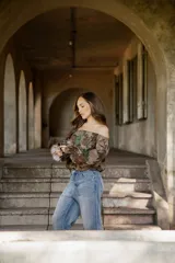 Blusa de lino con diseño off-shoulder, mangas largas amplias y estampado floral en tonos tierra y verdes.