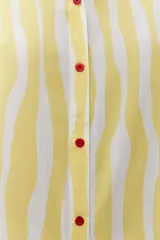 Vestido camisero amarillo con rayas verticales blancas, sin mangas y con botones rojos.