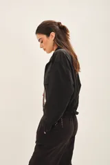 Campera negra de estilo militar o utilitario, con cuello alto, bolsillos delanteros con tapa y cordón ajustable en el ruedo.