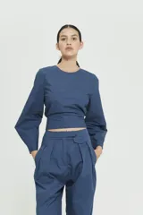 Top azul con corte crop, mangas largas acampanadas y espalda descubierta.