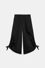 Pantalón culotte de tiro medio, color verde militar, con cintura elástica y bolsillos laterales ocultos. Presenta un diseño de bajo ancho con aberturas ajustables mediante cordones fruncidos en los laterales.