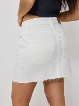 Falda de jean blanca de corte recto y tiro medio, con diseño de cinco bolsillos, cierre frontal con botón metálico y ruedo deshilachado.