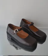 Zapatos Mary Jane color marrón oscuro de cuero, con punta cuadrada, tira sobre el empeine con hebilla metálica plateada y plataforma con suela track.