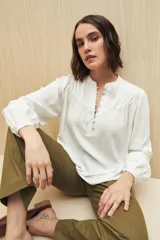 Camisa verde claro de viscosa suave, con cuello mao y botonadura parcial al frente. El detalle de frunces en los hombros y los puños abotonados le suman delicadeza y estilo.