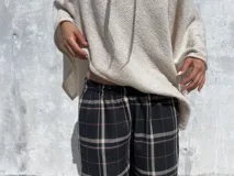 Pantalón de corte holgado y silueta tipo barrel, confeccionado en tela viyela con estampado de cuadrillé en tonos negro, beige y líneas finas rojizas. Presenta cintura elástica y puños ajustados en el tobillo.