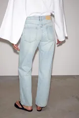 Jeans de mezclilla en color negro gastado, tiro bajo, corte de pernera recta y diseño clásico de cinco bolsillos con cierre frontal de cremallera y botón metálico.