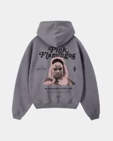 Canguro con capucha de corte regular en color gris con efecto stone wash. Presenta un estampado gráfico en la espalda inspirado en la película Pink Flamingos, con la imagen de Divine y tipografía en negro y rosa.