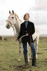 Blazer rosa de terciopelo con solapa en V, dos botones dorados y bolsillos laterales.