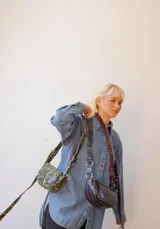 Bandolera de cuero color rojo con detalles en negro, con correa regulable y cierre superior con cremallera.