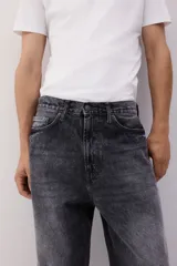 Pantalón de jean de cinco bolsillos, confeccionado en denim de algodón rígido. Modelo de corte baggy, holgado desde la cadera hasta el bajo, con piernas redondeadas extraamplias y pliegues en el tobillo. Presenta cintura clásica con cierre y tiro bajo.