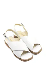 Sandalia baja de cuero charol color blanco, con tiras cruzadas en el empeine y tira trasera con hebilla.
