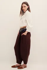 Pantalón babucha negro de lino, de corte holgado estilo barrel con pinzas en la cintura y bolsillos laterales.