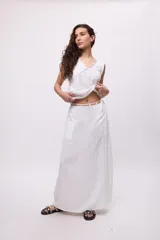 Falda larga blanca de algodón con textura, estilo envolvente (wrap) y talle bajo ajustable con un caderín de lazo fino.