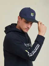 Gorra azul marino con visera negra y parche con el logo de Rusty en el frente.