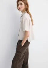 Camisa de manga corta con diseño a rayas, cuello camisero, silueta regular, largo crop, bolsillo tipo parche en el frente y cierre de botones.