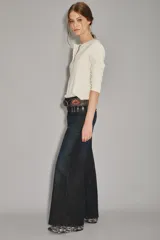 Jean de corte oxford y tiro alto, confeccionado en denim azul oscuro con un ligero lavado. Presenta un diseño de pierna ancha que se ensancha desde la cadera hacia el ruedo, con cierre y botón frontal.