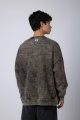 Buzo de cuello redondo con efecto de teñido artesanal acid wash. Presenta un corte oversize, mangas largas con puños acanalados y etiqueta pequeña en el puño izquierdo.
