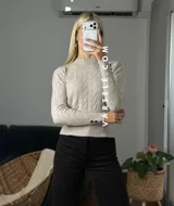 Sweater de tejido de punto con diseño de trenzas verticales, cuello redondo y mangas largas con puños ajustados que presentan detalle de botones metálicos.