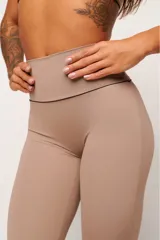 Conjunto deportivo de top y calzas color tostado, confeccionado en poliamida de alta performance con detalles de vivo contrastante. El top cuenta con breteles anchos y diseño slim, mientras que la calza presenta un diseño minimalista de tiro alto.