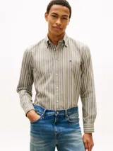 Camisa de manga larga Tommy Hilfiger de corte regular, confeccionada en popelín de algodón color beige con rayas verticales texturizadas en tonos blancos y oscuros. Presenta cuello con botones, puños redondeados y el logo de la marca bordado en el pecho.