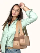 Bolso tipo baguette de cuero genuino color marrón claro, con dos compartimentos frontales con solapa y un parche de gamuza con el logo de un búho grabado. Posee una correa ancha de cuero ajustable.