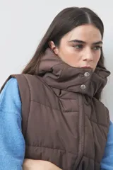 Chaleco puffer negro con diseño acolchado, capucha desmontable y cierre frontal. Cuenta con cordones ajustables en la cintura y bolsillos laterales.