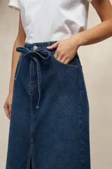 Falda larga de denim color marrón chocolate, tiro alto, con lazo de ajuste en la cintura y abertura frontal pronunciada.