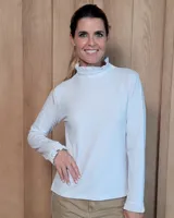 Polera de manga larga color blanco, confeccionada en algodón, con cuello alto tipo tortuga y detalles de volados en el cuello y en los puños.