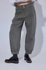 Pantalón de corte holgado tipo bombachita, confeccionado en Tencel. Presenta pinzas en la cintura, cierre frontal con doble botón dorado y bolsillos delanteros. El ruedo cuenta con un sistema de ajuste mediante botón dorado.