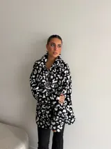 Buzo de peluche con estampado animal print, cuello alto con cierre frontal parcial y detalle de etiqueta decorativa en el pecho.