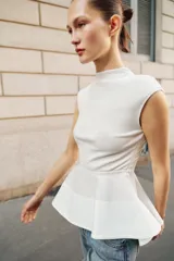 Top blanco sin mangas con cuello perkins y bajo con volado tipo peplum.