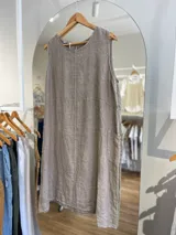 Vestido corto blanco de lino, sin mangas, con cuello redondo y bolsillos laterales. Tiene cierre con botones en la espalda.